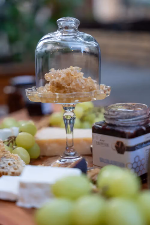Verkostung: Honig, Käse und Trauben auf einem Holzbrett